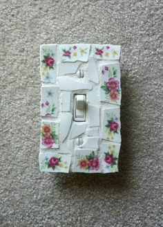 a flowered light switch plate on the floor next to a carpeting area with a white wall