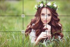 a woman with flowers in her hair is sitting in the grass and looking at the camera