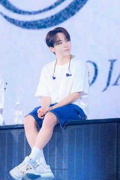 a young man sitting on top of a blue bench next to a white and black wall