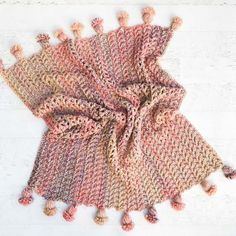 a knitted scarf with pom poms on it