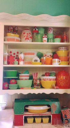 the shelves are full of colorful dishes and bowls on it's sides, including one that has been painted green