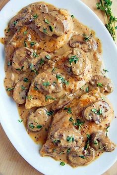 a white plate topped with chicken covered in mushroom gravy and garnished with parsley