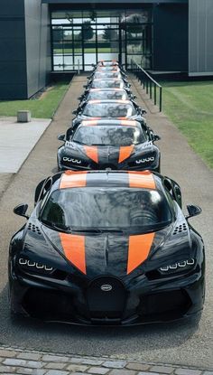 a row of black and orange sports cars parked in front of a building