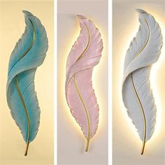 three different colored feathers are shown on the wall, one is blue and one is pink