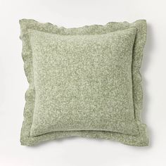 a green pillow with scalloped edges on a white background