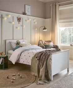 a bedroom with white furniture and lights on the headboard, bedding and rugs