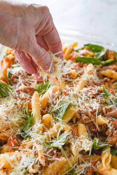 someone is sprinkling parmesan cheese on top of pasta in a pan