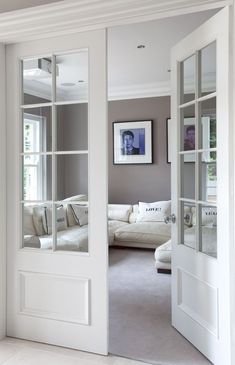 an open door leading to a living room with white walls and furniture in the background