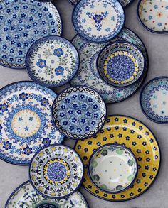 many plates and bowls are arranged together on the table, one is blue and yellow