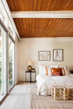 a bedroom with wood ceiling and white bedding, wooden slats on the floor