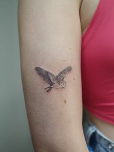 a woman with a tattoo on her arm is wearing a pink shirt and has a small bird