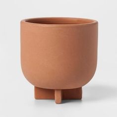 a small clay pot sitting on top of a wooden stand in front of a white background