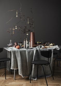 the table is set with two black chairs and a gray cloth draped over it's top