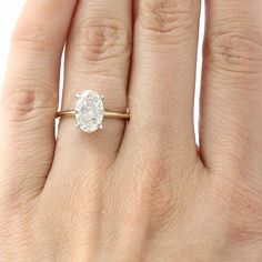 a woman's hand with a diamond ring on top of her finger, showing the center stone