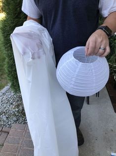 a man holding a white paper lantern in one hand and a plastic bag in the other