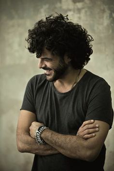 a man with curly hair and a watch on his wrist