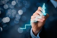 a man in a business suit is drawing a stair up arrow on a glass screen