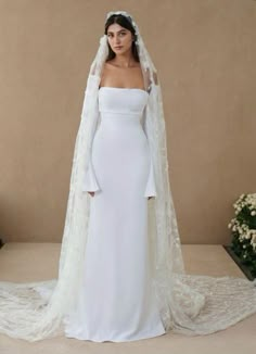 a woman wearing a white wedding gown with a long veil on her head and shoulders