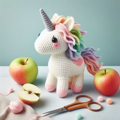 a crocheted unicorn next to an apple and scissors