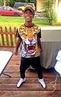 a young man standing on top of a wooden deck wearing a t - shirt with an image of a tiger