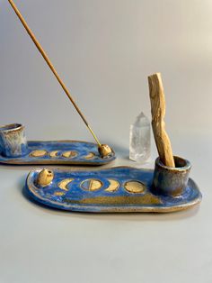 two blue and gold dishes with wooden sticks sticking out of them