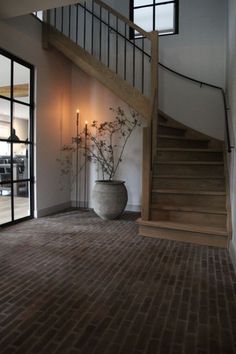 a large vase sitting on top of a wooden floor next to a stair case in a building