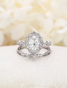 a diamond engagement ring with white flowers in the background