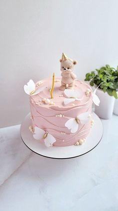 a pink cake with white butterflies and a dog figurine sitting on top of it