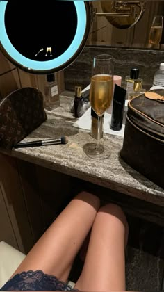 a woman's legs resting on a counter in front of a vanity with makeup and cosmetics