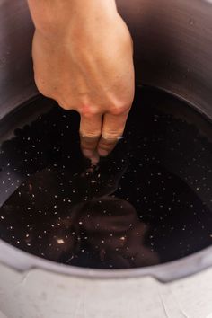 a person is stirring something in a pot with water and ice cubes on the bottom