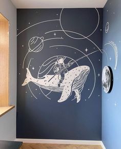 a room with a wall painted with an image of a whale and planets on it