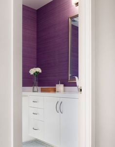 a bathroom with purple walls and white cabinets