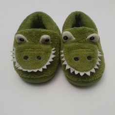 a pair of green slippers with an alligator's head on the front and bottom