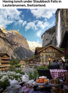 a table with food on it in front of some mountains and buildings that look like waterfalls