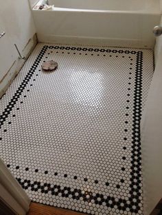 a bathroom with black and white tiles on the floor, and a bathtub in the corner