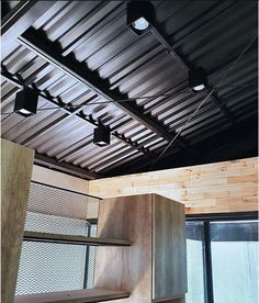 an empty room with wooden shelves and metal ceiling lights in the corner, next to a sliding glass door