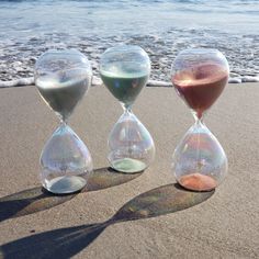 three hourglasses sitting on the sand at the beach