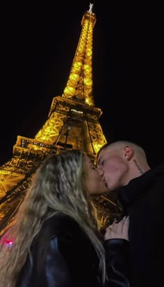 a man and woman kissing in front of the eiffel tower at night, paris