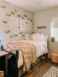 a bedroom with a bed, desk and pictures on the wall above it is decorated with greenery