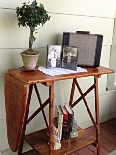 a wooden table topped with books next to a potted plant