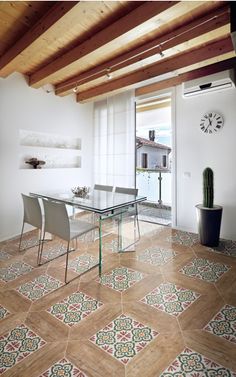 a dining room with tiled flooring and wooden beams on the ceiling, along with a glass table surrounded by white chairs