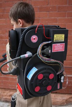 a young boy is holding up a movie projector with wires and cords on it