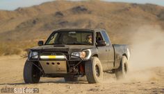 the truck is driving through the desert with dust coming off it's back wheels