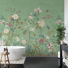 a bath tub sitting next to a green wall with flowers painted on the walls and floor