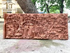 an intricately carved red brick with trees and buildings in the background, sitting on concrete