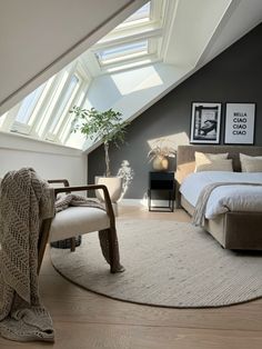 an attic bedroom with a bed, couch and chair in the corner under a slanted skylight