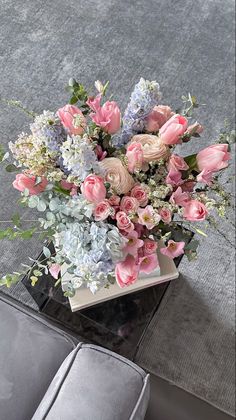 a vase filled with pink and white flowers on top of a table next to a couch