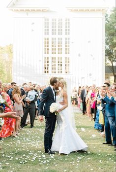 a bride and groom kissing in front of a crowd of people