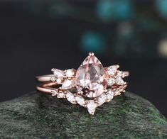 a pink diamond ring sitting on top of a green rock