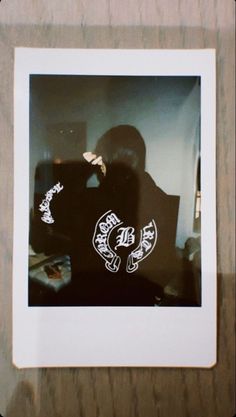 a person sitting in front of a wooden table with a polaroid print on it